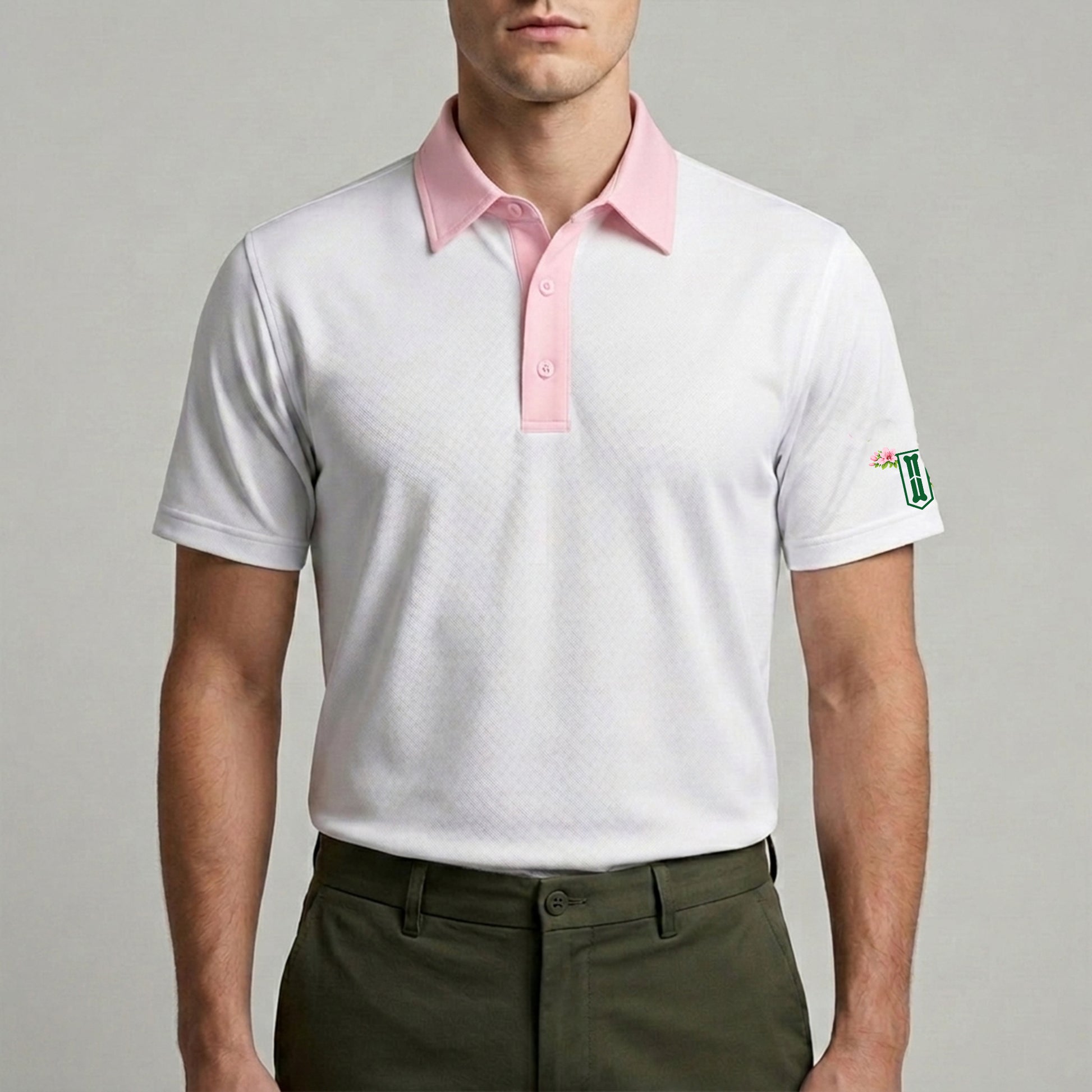 Man wearing a white polo shirt with pink collar and green logo on a gray background