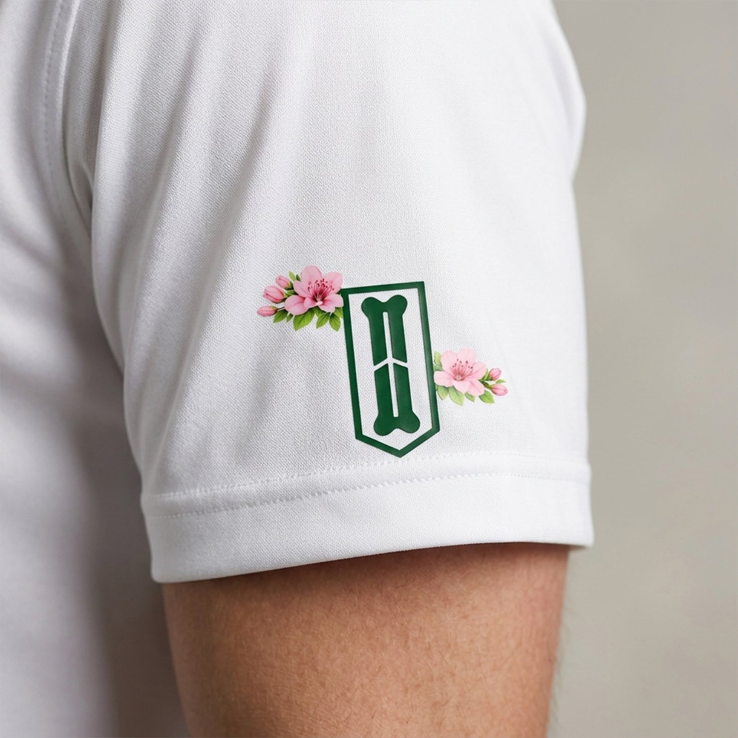 White sleeve with green logo and pink flowers on a neutral background