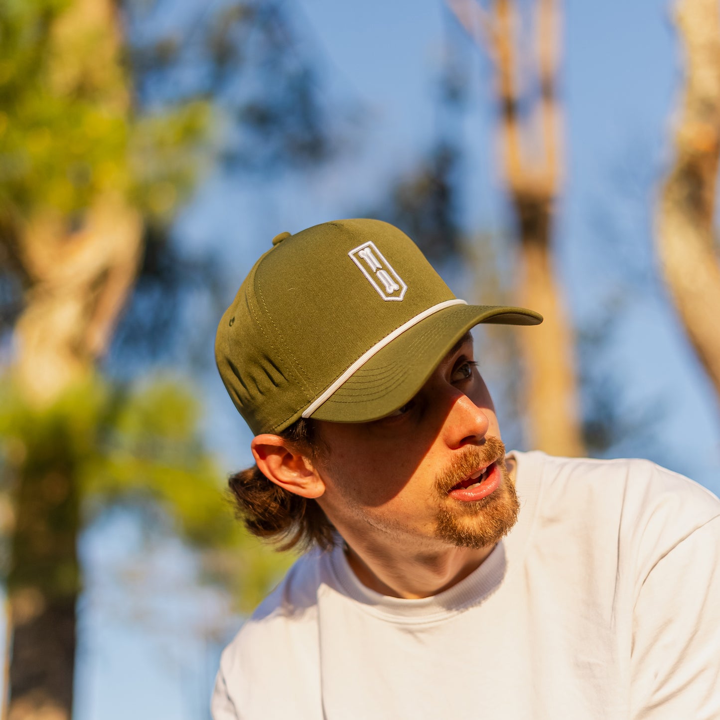 Man wearing a green golf cap with a logo outdoors